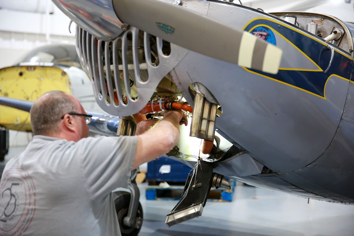 Technician working on the landing gear of a vintage aircraft